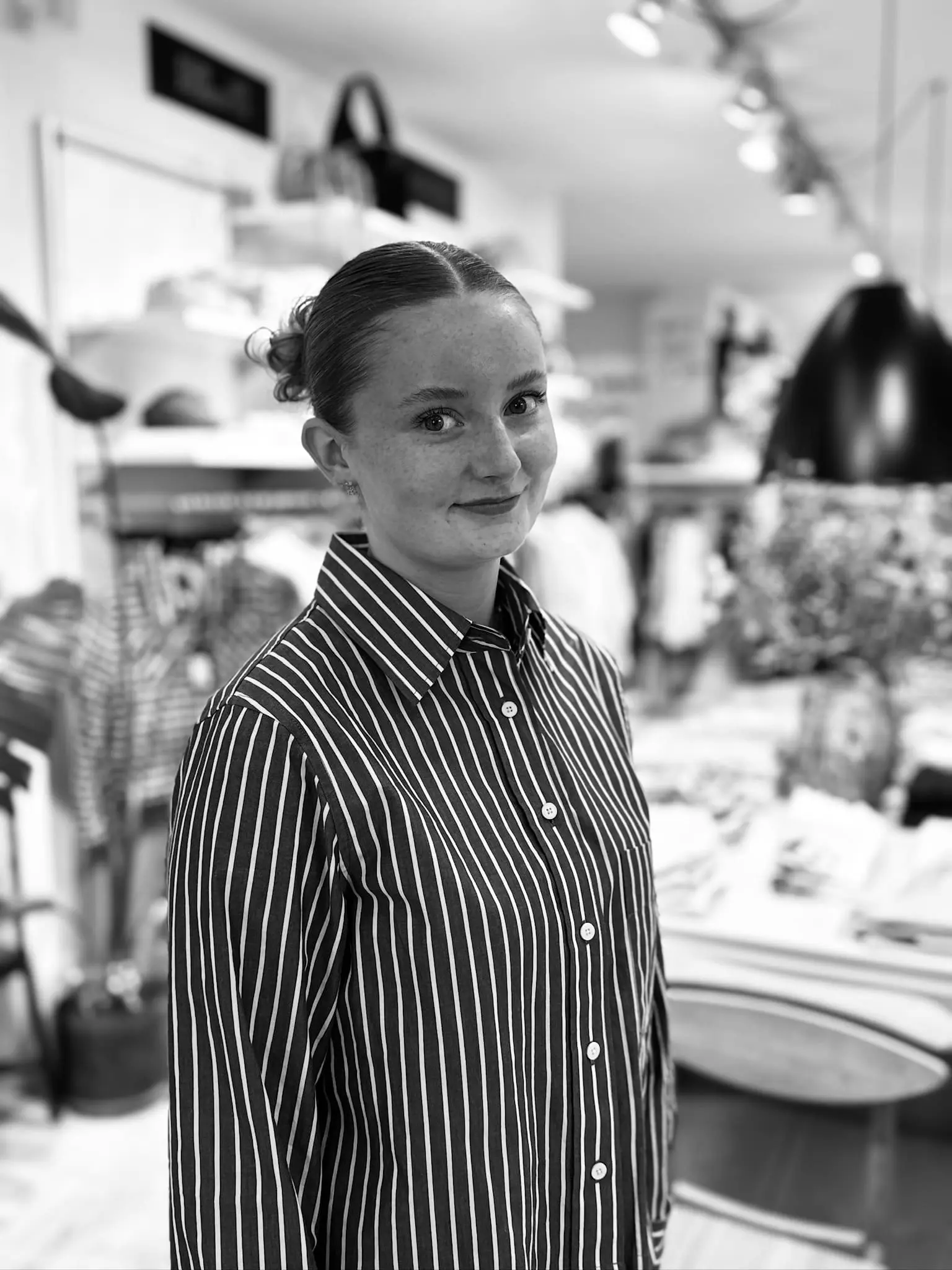 Portræt af smilende kvinde i sort og hvid stribet skjorte i Hinges Hus butik.